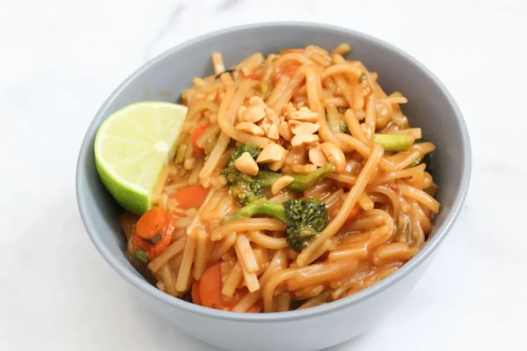 finished pad thai dish topped with chopped peanuts and lime wedge