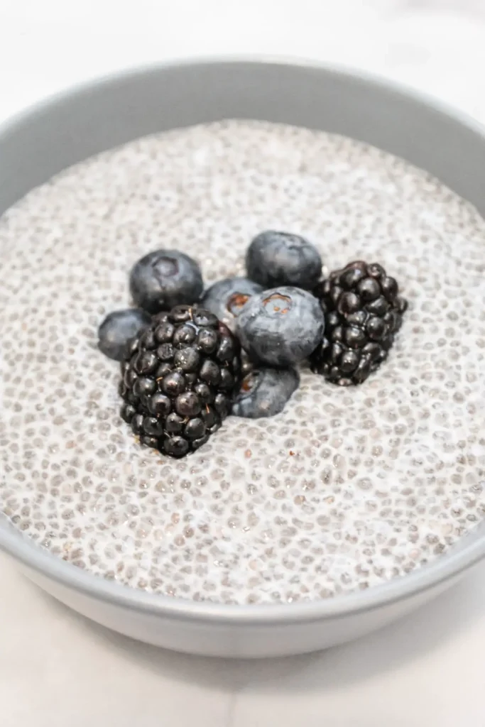 chia seed pudding mixture in a blue bowl on a white marble background