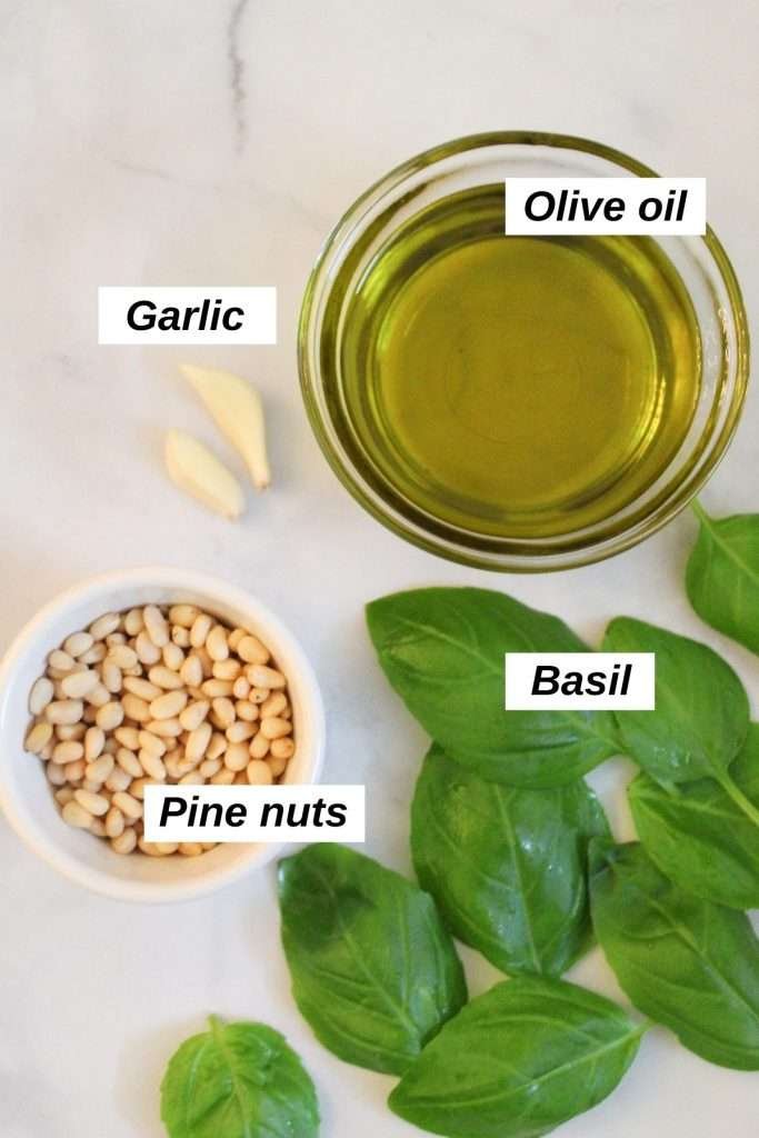 individual ingredients for vegan pesto sauce recipe on a white marble background