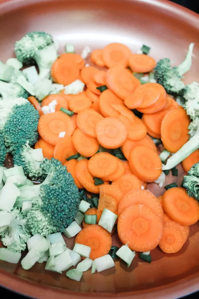saute broccoli, garlic, carrots, scallions, ginger, and olive oil in a pan. 