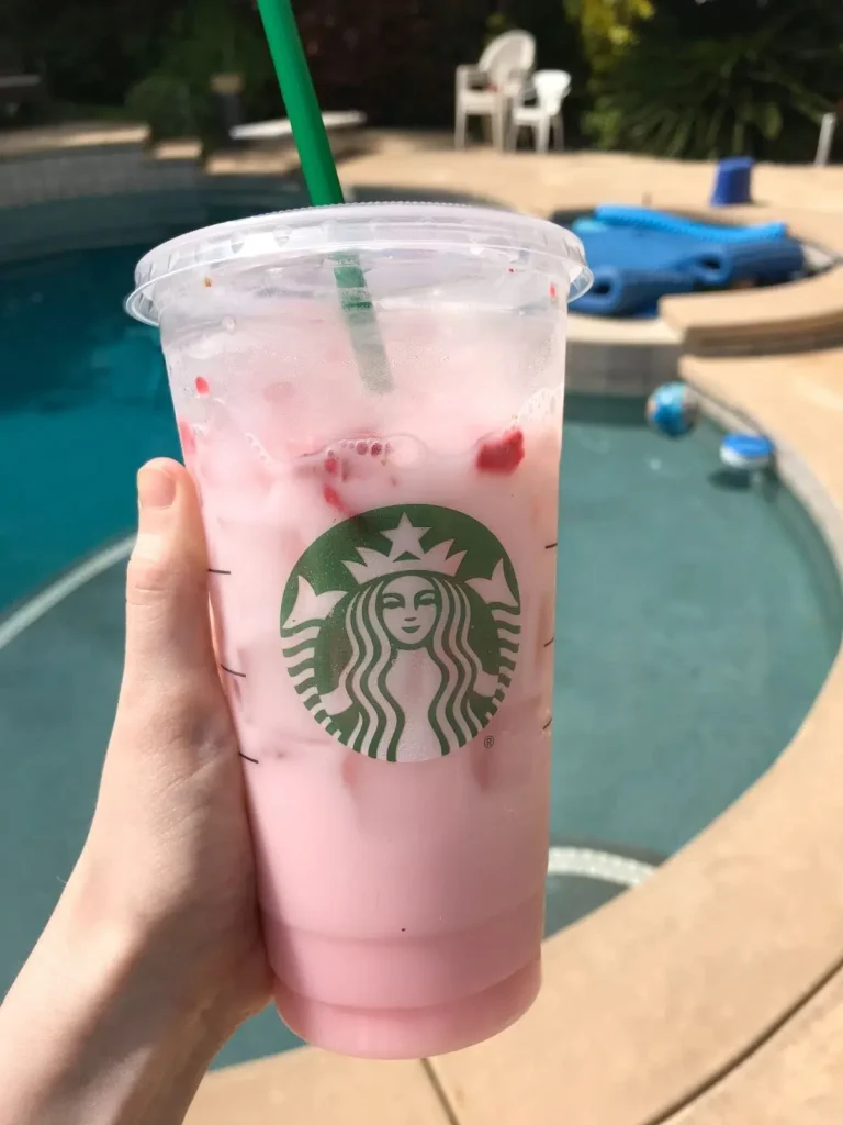 venti starbucks pink drink with a pool in the background