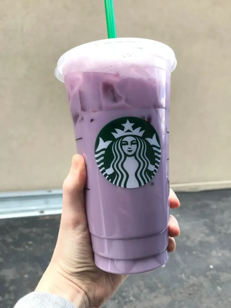 starbucks purple drink made with passion tea and soy milk in front of a tan wall