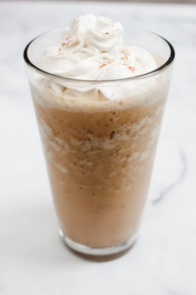 vegan pumpkin spice cream frap in a clear glass cup on a white background