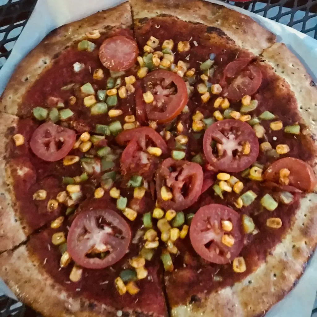 veggie pizza from pizza studio with rosemary herb crust, tomatoes, corn, green bell peppers, and red sauce