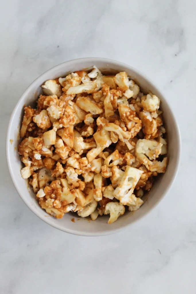 mixing together the thai pizza sauce and chopped up cauliflower