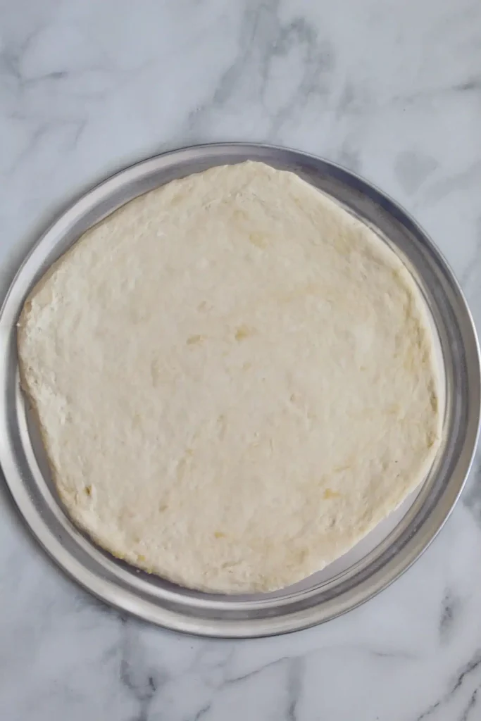 rolled out vegan pizza dough on pizza pan