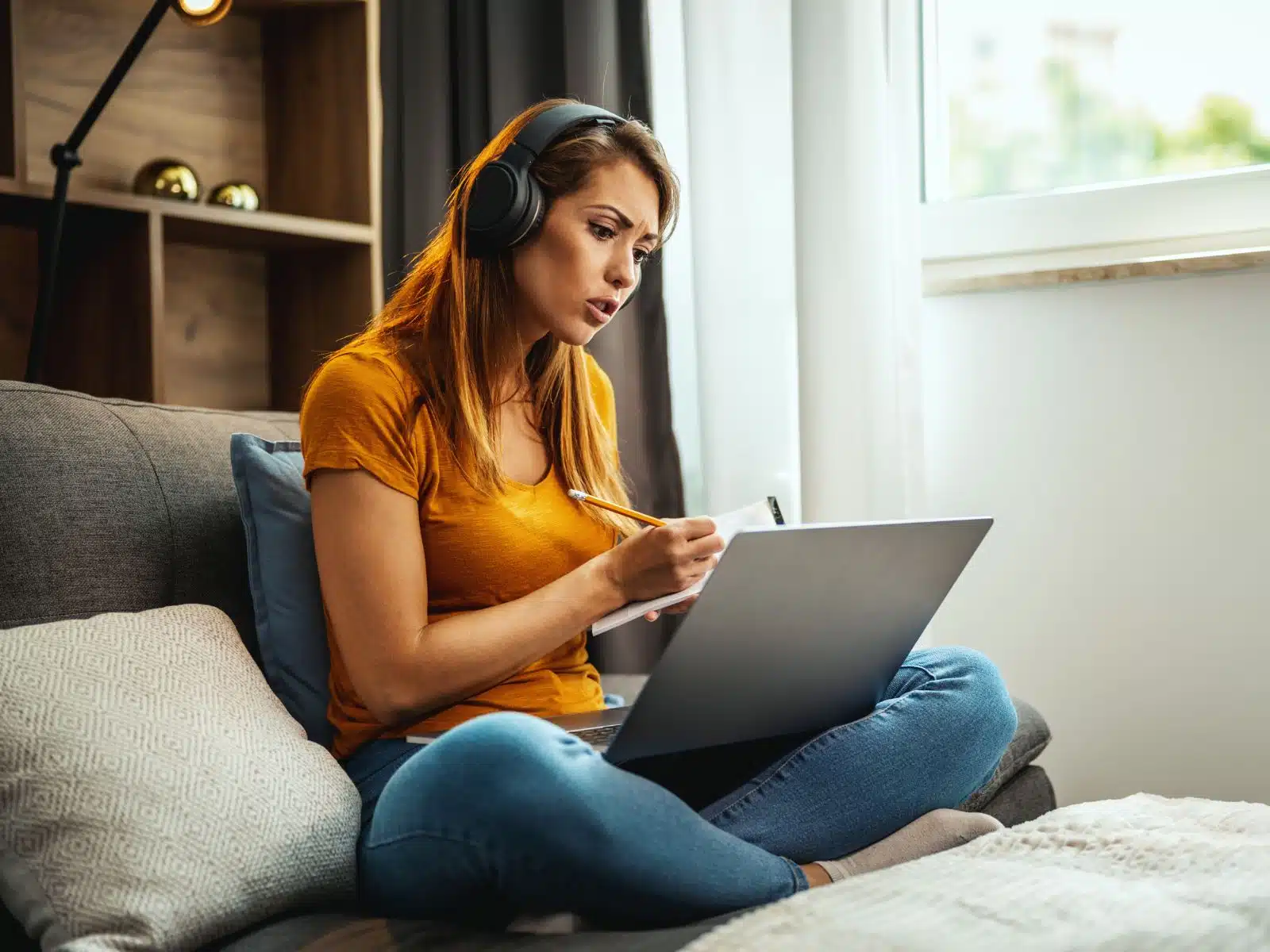 woman sitting on couch with a laptop and notepad